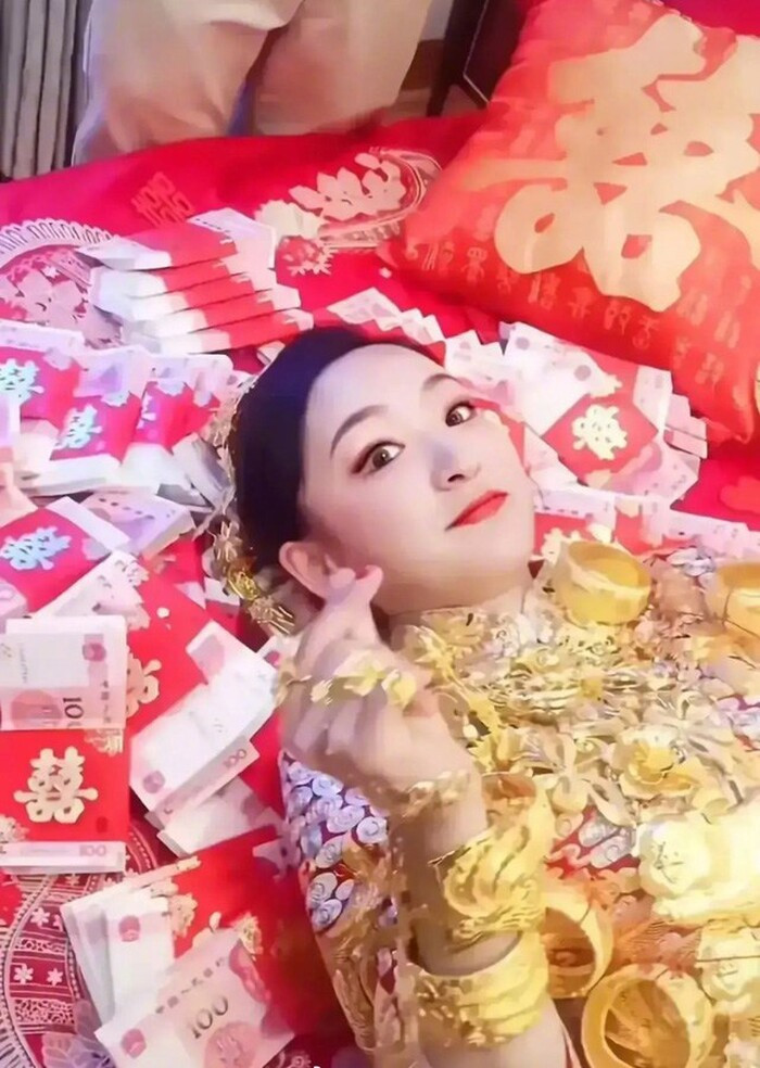 Cô dâu khoe vàng đeo trĩu cổ, nằm trên giường cưới rải hàng xấp tiền khiến dân tình thầm ghen tị