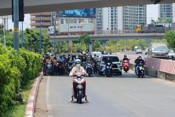 Nắng nóng khiến người đi đường tìm bóng mát để dừng đèn đỏ. Ảnh: Trần Minh