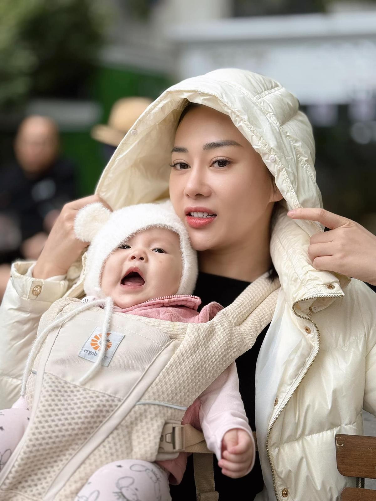 Có thể là hình ảnh về 1 người, em bé, áo phao lông vũ và áo dạ khuy sừng
