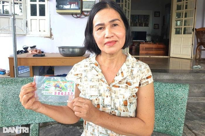 Bà Nguyệt cầm trên tay tờ vé số trúng độc đắc nhưng không được trả thưởng. Ảnh: Dân Trí