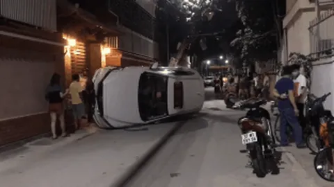 Xế hộp đâm gãy cột điện rồi lật nghiêng giữa đường, người trong xe bò ra từ cửa sổ trời