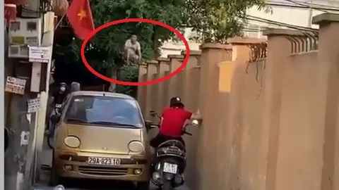 Xe máy và ô tô quyết không nhường đường, bao phương tiện dừng chờ, người dân leo lên tường để 'hóng'