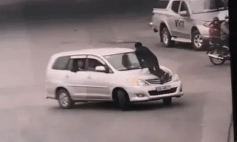 Kinh hãi cảnh nữ tài xế vẫn chạy xe băng băng trên đường Hà Nội bất chấp lái xe taxi đu bám trên nắp capo