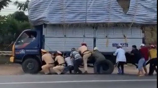 CLIP: CSGT và gần 10 người đàn ông còng lưng cứu xe tải quá khổ